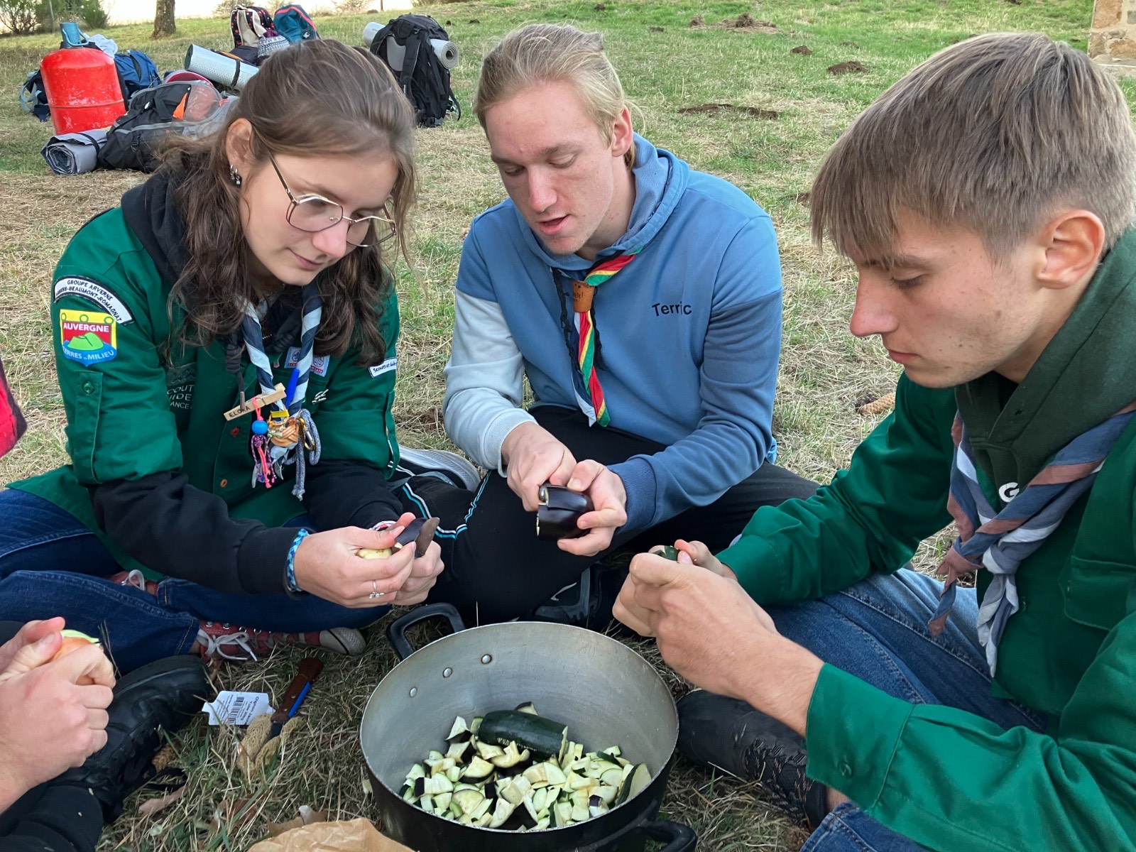 Épluchage des légumes pour le repas, autour de la marmite au camp