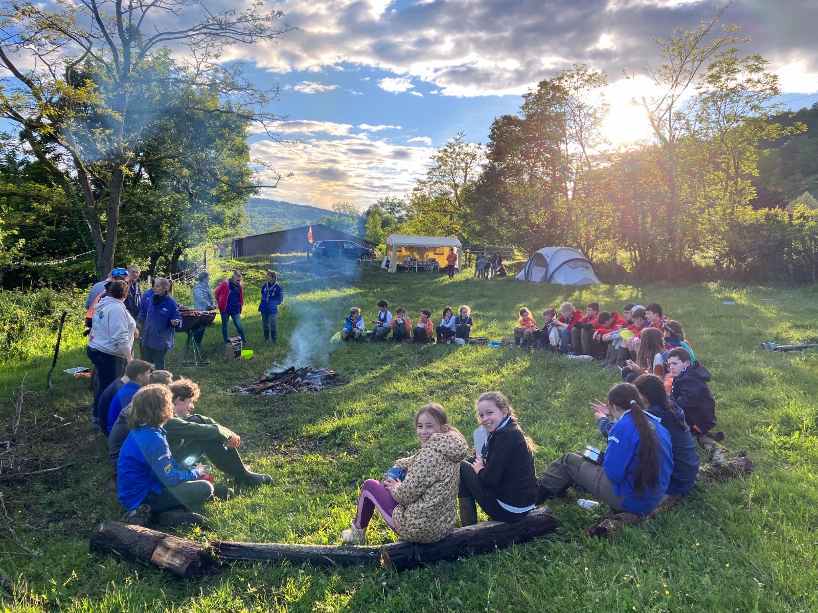 Tout le groupe réuni en cercle autour du feu, au coucher du soleil